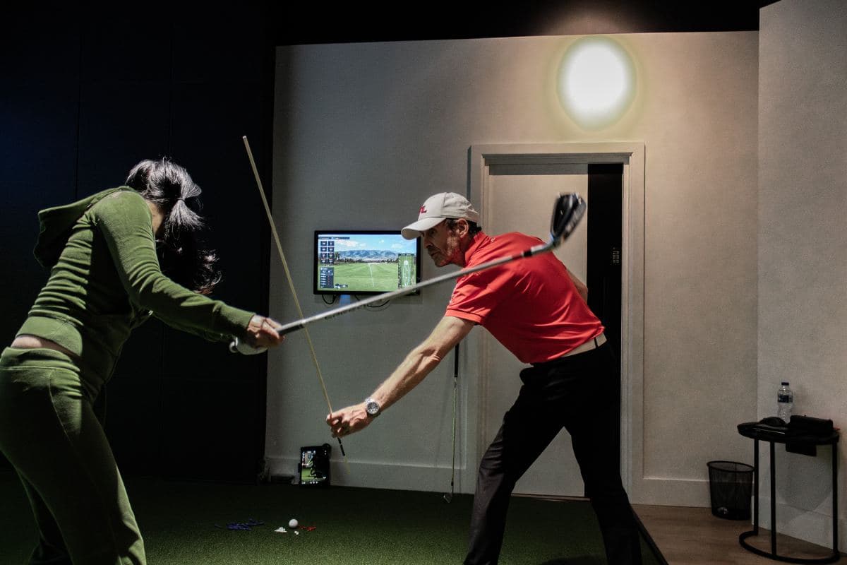A PGA coach correcting a player's swing in a bay