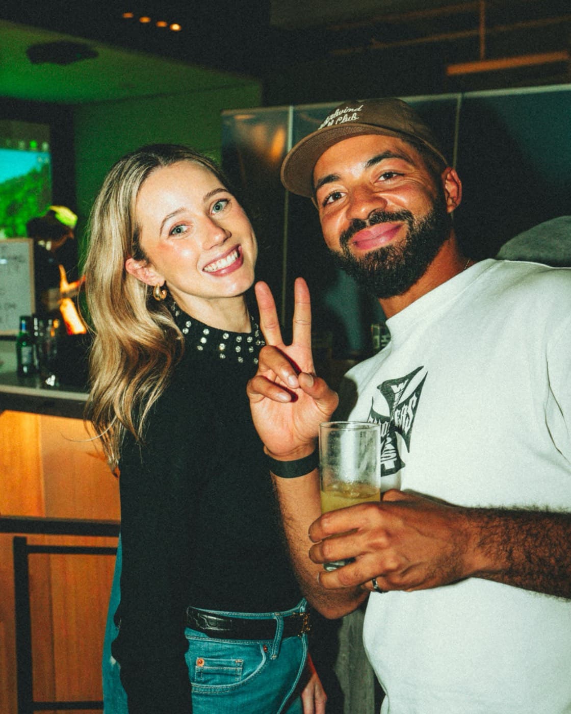 Two friends at the bar at Caddi Club, drinks in hand
