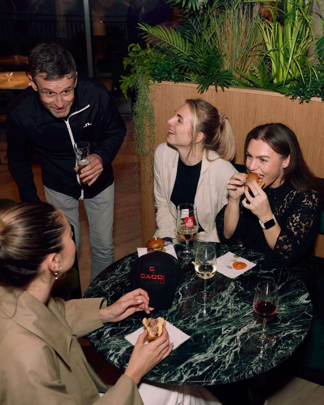 Friends eating sliders with wine at Caddi Club