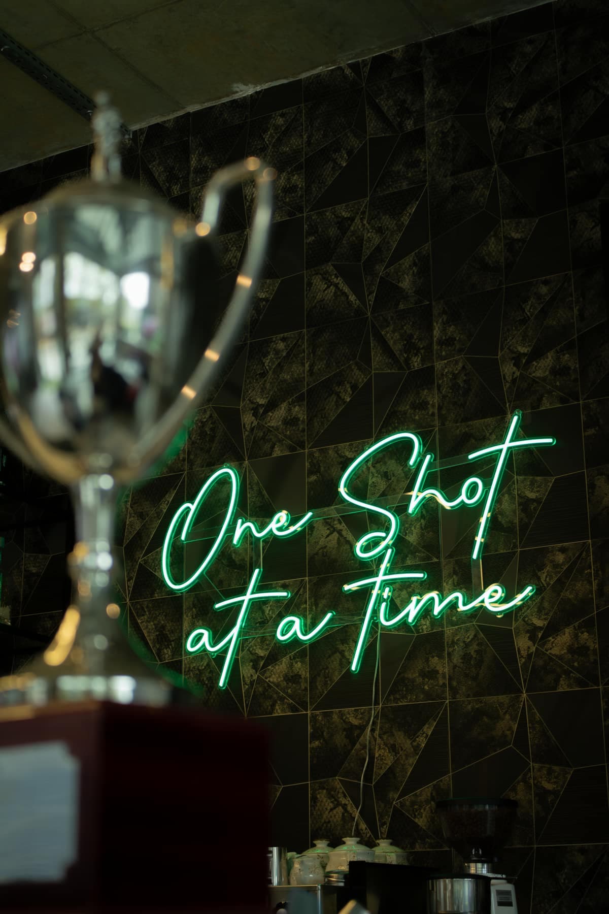 The 'One shot at a time' neon and club trophy at Caddi Club Chelsea