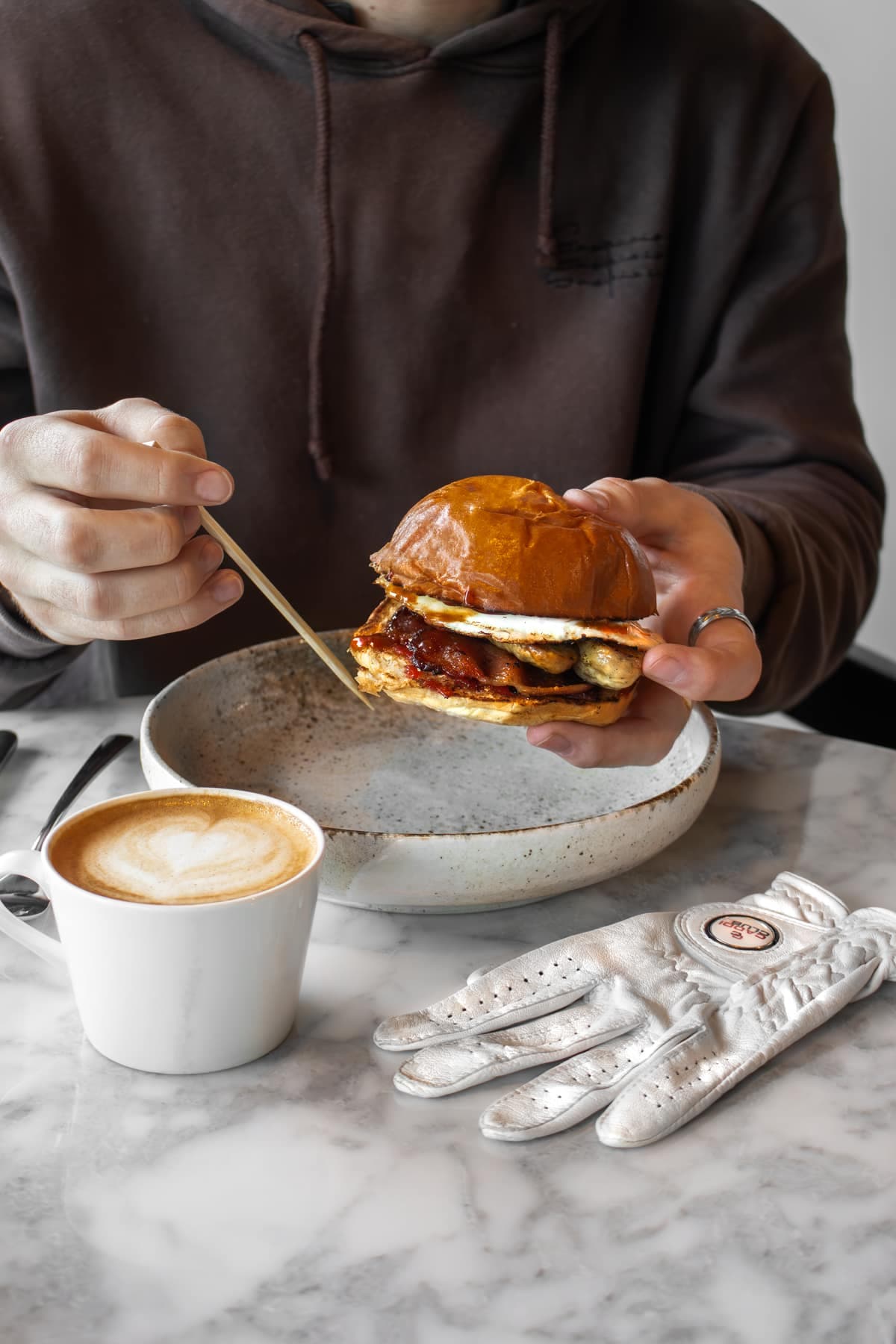 Brunch and a flat white beside a golf glove at Caddi Club Fulham