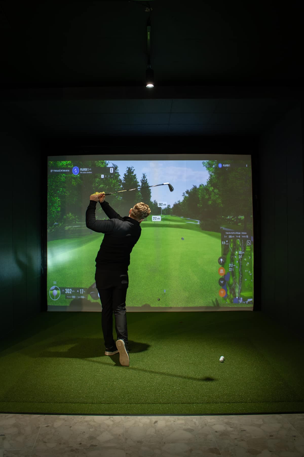 A player mid-swing in a bay at Caddi Club Fulham