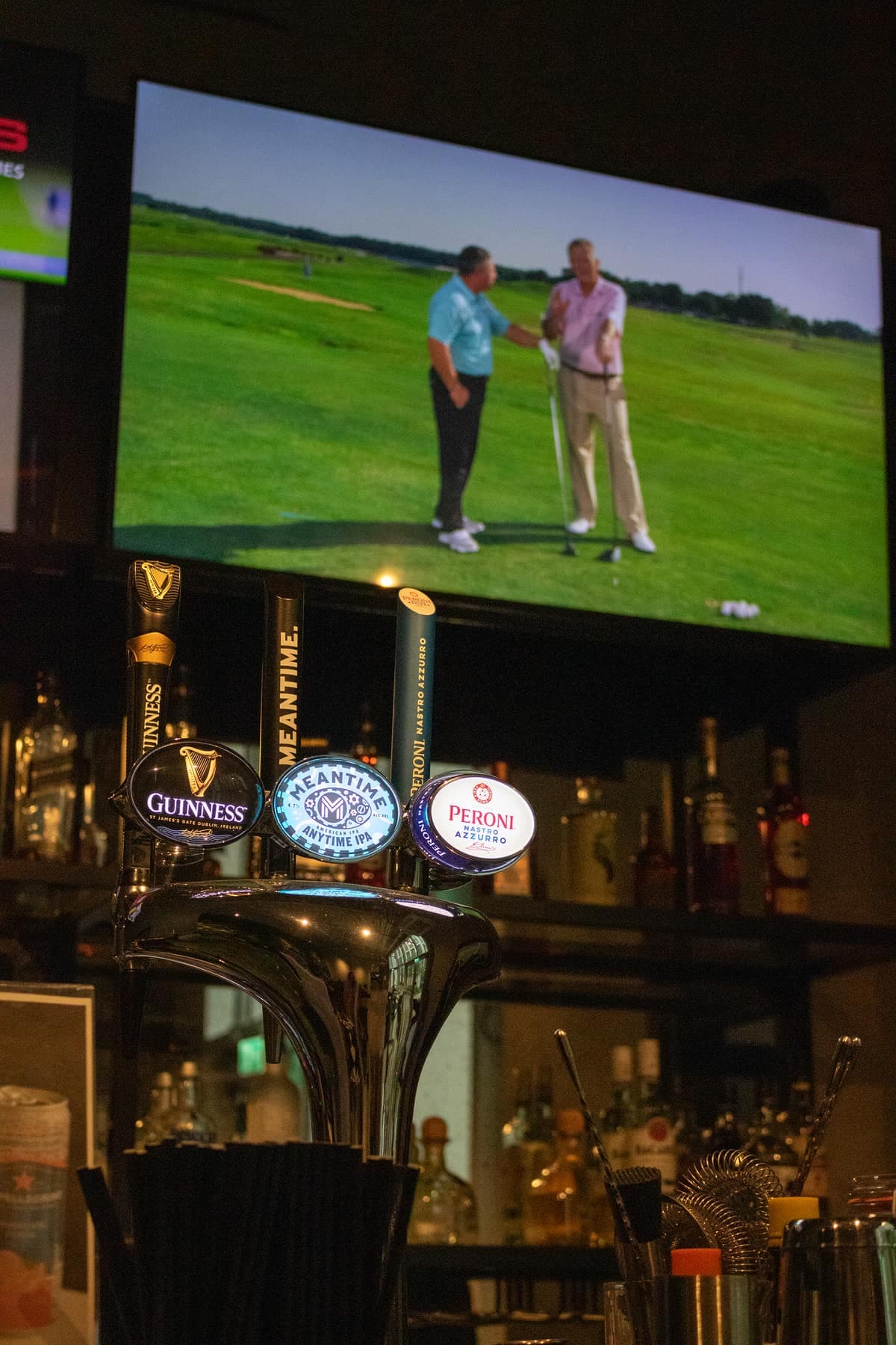 Beer taps at the bar at Caddi Club Waterloo, golf on the screen